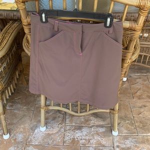 Brown skort for golf or casual wear. Has pink threading around pockets